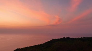 Güneşin rengarenk gökyüzünde batışı okyanus yüzeyine çarpıyor. Uçurumun güzelliği güzel günbatımının büyüleyici doğasına mükemmel uyuyor. Bulut manzarası arka plan 4k rengarenk kırmızı günbatımı gökyüzü.