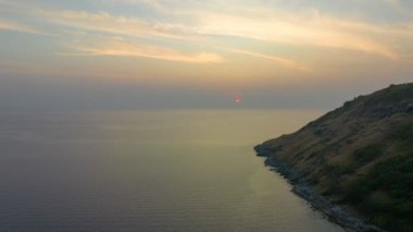 Güneşin rengarenk gökyüzünde batışı okyanus yüzeyine çarpıyor. Uçurumun güzelliği güzel günbatımının büyüleyici doğasına mükemmel uyuyor. Bulut manzarası arka plan 4k rengarenk kırmızı günbatımı gökyüzü.