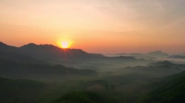 Dağ sırtı üzerinde hava manzarası nefes kesici bir gün doğumu. Karanlık vadide sisli, renkli ışık yalağı manzarası. Gökyüzü dokusu, inanılmaz soyut doğa arkaplanı.