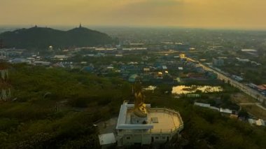 Gökyüzü hipervane manzaralı sarı gökyüzü, altın büyük Buda 'nın üzerinde. Yüksek dağdaki altın Buda, Phetchaburi şehrinin arka planındaki Wat Ta It Phetchaburi.parlak sarı gökyüzü..