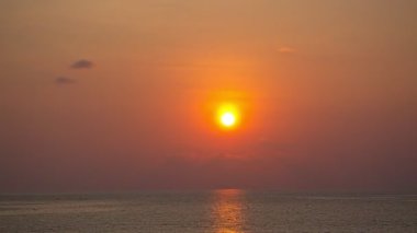 Güneş denizin üzerinde batarken gökyüzü sarıdan kırmızıya döner gün batımı doğanın inanılmaz ışığı bulutlu gökyüzü. - Büyük güneş ve kırmızı ışıklı gökyüzü arkaplanı. 4k çözünürlüğü