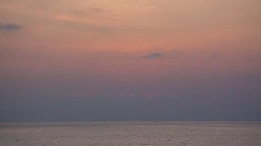 Güneş denizin üzerinde batarken gökyüzü sarıdan kırmızıya döner gün batımı doğanın inanılmaz ışığı bulutlu gökyüzü. - Büyük güneş ve kırmızı ışıklı gökyüzü arkaplanı. 4k çözünürlüğü