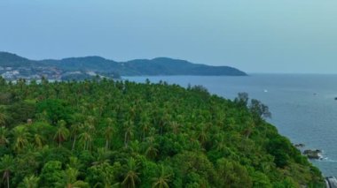 Kayaların ve tepelerdeki yeşil ormanın yanında turkuaz deniz manzarası. Adayı çevreleyen kayalar. Dalgalar Phuket Adası 'ndaki kayalara çarptı. kayaların doku arkaplanı