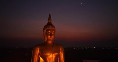 .Ay, dünyanın en büyük altın Buda 'sının kafasının üstündeydi. Alacakaranlıkta. Wat Muang Ang Thong Tayland 'da popüler ve ünlü bir mekan olan Altın Gece Atmosferi.