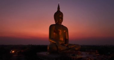 .Ay, dünyanın en büyük altın Buda 'sının kafasının üstündeydi. Alacakaranlıkta. Wat Muang Ang Thong Tayland 'da popüler ve ünlü bir mekan olan Altın Gece Atmosferi.