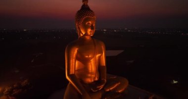 Ay, dünyanın en büyük altın Buda 'sının kafasının üstündeydi. Alacakaranlıkta. Düşük gece atmosferi Altın Büyük Buda Wat Muang Ang Tanga Tayland 'da ünlü bir simgedir.