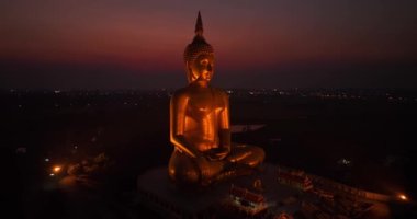 Ay, dünyanın en büyük altın Buda 'sının kafasının üstündeydi. Alacakaranlıkta. Düşük gece atmosferi Altın Büyük Buda Wat Muang Ang Tanga Tayland 'da ünlü bir simgedir.