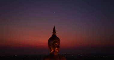 Ay, dünyanın en büyük altın Buda 'sının kafasının üstündeydi. Alacakaranlıkta. Düşük gece atmosferi Altın Büyük Buda Wat Muang Ang Tanga Tayland 'da ünlü bir simgedir.