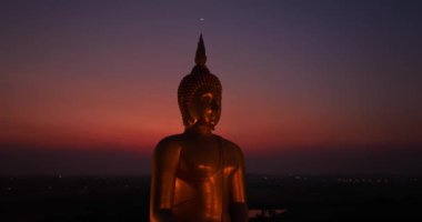 Ay, dünyanın en büyük altın Buda 'sının kafasının üstündeydi. Alacakaranlıkta. Düşük gece atmosferi Altın Büyük Buda Wat Muang Ang Tanga Tayland 'da ünlü bir simgedir.