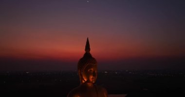 Ay, dünyanın en büyük altın Buda 'sının kafasının üstündeydi. Alacakaranlıkta. Düşük gece atmosferi Altın Büyük Buda Wat Muang Ang Tanga Tayland 'da ünlü bir simgedir.