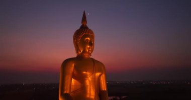 Ay, dünyanın en büyük altın Buda 'sının kafasının üstündeydi. Alacakaranlıkta. Düşük gece atmosferi Altın Büyük Buda Wat Muang Ang Tanga Tayland 'da ünlü bir simgedir.