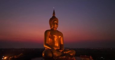 Ay, dünyanın en büyük altın Buda 'sının kafasının üstündeydi. Alacakaranlıkta. Düşük gece atmosferi Altın Büyük Buda Wat Muang Ang Tanga Tayland 'da ünlü bir simgedir.