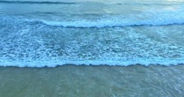 Karon sahili Phuket Tayland 'da hava dalgaları kıyıya çarpıyor. Sarı günbatımında pürüzsüz dalgalar. Mavi deniz ve temiz kum manzarası. Cennet plajı.