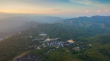 Günbatımında tepenin zirvesinde medeniyetten uzak köy zorlu bir yolda ilerliyor.