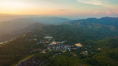 Günbatımında tepenin zirvesinde medeniyetten uzak köy zorlu bir yolda ilerliyor.