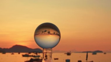 Kristal kürenin içinde gün doğumunda renkli bir doğa. Altın denizdeki kristal kürede balıkçı tekneleri.
