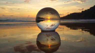 Kristal küreyi sular altında bırakan denizin yansımasında kristal kürenin içinde gün batımında muhteşem bir gökyüzü manzarası. Su yüzeyindeki parlak sarı gökyüzünün yansıması..