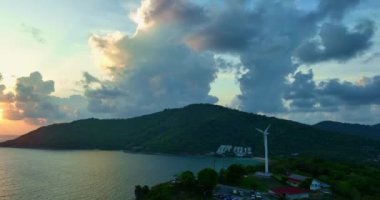 Hava manzaralı rüzgar türbini günbatımında güzel tropikal mavi gökyüzü Ya Nui Sahili, Phuket, Tayland 'da. Ufkun sonundaki bulutların arasından ışık saçar.