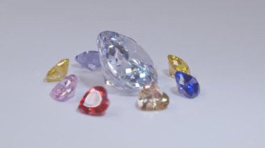 .Kalp şeklinde elmaslar sarı safir elmas ve pembe safir elmaslar ve beyaz bir arka planda dönüyor...