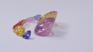 .Kalp şeklinde elmaslar sarı safir elmas ve pembe safir elmaslar ve beyaz bir arka planda dönüyor...