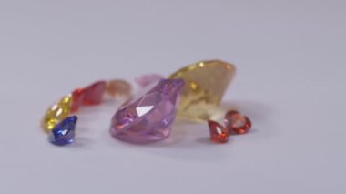 .Kalp şeklinde elmaslar sarı safir elmas ve pembe safir elmaslar ve beyaz bir arka planda dönüyor...
