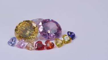 .Kalp şeklinde elmaslar sarı safir elmas ve pembe safir elmaslar ve beyaz bir arka planda dönüyor...