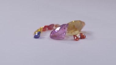 .Kalp şeklinde elmaslar sarı safir elmas ve pembe safir elmaslar ve beyaz bir arka planda dönüyor...