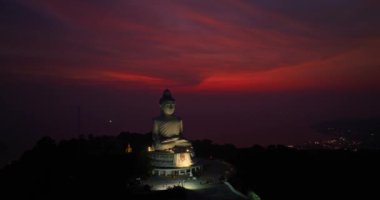 Phuket Büyük Buda 'nın gökyüzü manzarası. Phuket adasının tepesindeki önemli ve saygı duyulan simgeler. Mor gökyüzünde renkli kırmızı bulut.