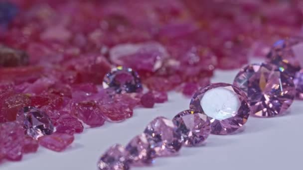 不同尺寸和不同形状的粉红蓝宝石被放置在白色地面的中间 周围是未经切割的红石榴石 优质4K影片 — 图库视频影像