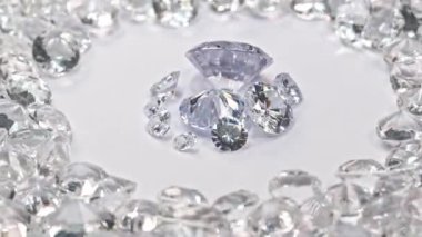 Özel olarak seçilmiş elmaslar beyaz elmaslar yığınının içinde. Çeşitli boyutlarda rengarenk elmaslar beyaz arka planda bir merkez daireye yerleştiriliyor..