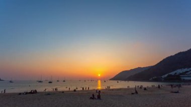 .Nai Harn plajında gün batımında altın gökyüzü... denizin ufuklarında... güzel altın gökyüzü boyunca uzanan yatlar... harika günbatımında Nai Harn plajında turist kalabalığı.....