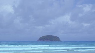 Yeşil denizden gelen yumuşak dalgalar beyaz uzun plaja vurur... güzel doğa sahilde... mavi gökyüzü arka planında beyaz bulut..