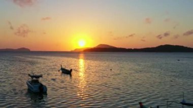 Balıkçı teknelerinin üzerindeki hava manzarası suda güzel bir yansıma yaratıyor. Balıkçı teknelerindeki güzel güneşin yansıması Phuket denizinde yüzüyor.