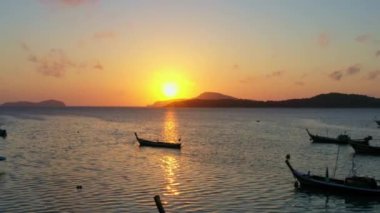 Balıkçı teknelerinin üzerindeki hava manzarası suda güzel bir yansıma yaratıyor. Balıkçı teknelerindeki güzel güneşin yansıması Phuket denizinde yüzüyor.