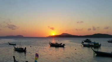 Balıkçı teknelerinin üzerindeki hava manzarası suda güzel bir yansıma yaratıyor. Balıkçı teknelerindeki güzel güneşin yansıması Phuket denizinde yüzüyor.