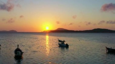 Balıkçı teknelerinin üzerindeki hava manzarası suda güzel bir yansıma yaratıyor. Balıkçı teknelerindeki güzel güneşin yansıması Phuket denizinde yüzüyor.