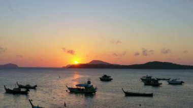 Balıkçı teknelerinin üzerindeki hava manzarası suda güzel bir yansıma yaratıyor. Balıkçı teknelerindeki güzel güneşin yansıması Phuket denizinde yüzüyor.