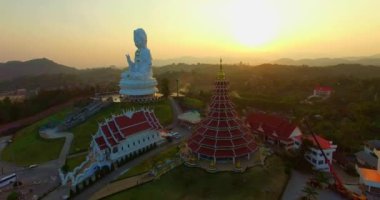 Hava manzarası harika. Dünyanın en büyük Guanyin 'i tatlı günbatımında. Çin tapınağının en büyük Guan Yin heykelinin önündeki güzel beyaz kilise. Wat Huay Pla Kang Chiang Rai Tayland 'da.