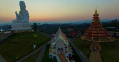 Hava manzarası harika. Dünyanın en büyük Guanyin 'i tatlı günbatımında. Çin tapınağının en büyük Guan Yin heykelinin önündeki güzel beyaz kilise. Wat Huay Pla Kang Chiang Rai Tayland 'da.