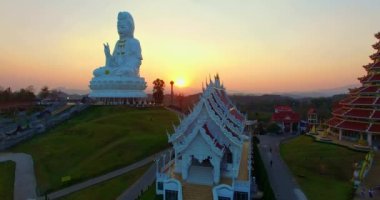 Hava manzarası harika. Dünyanın en büyük Guanyin 'i tatlı günbatımında. Çin tapınağının en büyük Guan Yin heykelinin önündeki güzel beyaz kilise. Wat Huay Pla Kang Chiang Rai Tayland 'da.