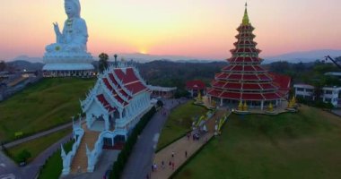 Hava manzarası harika. Dünyanın en büyük Guanyin 'i tatlı günbatımında. Çin tapınağının en büyük Guan Yin heykelinin önündeki güzel beyaz kilise. Wat Huay Pla Kang Chiang Rai Tayland 'da.