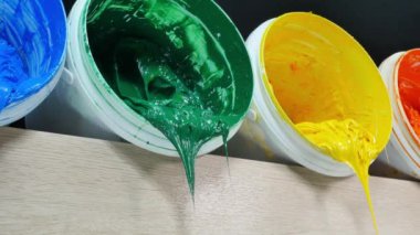 Yeşil sarı ve turuncu boyalar beyaz fıçıdan damlıyor... yüksek kaliteli 4K video. Renkli arkaplan boyası... Plastisol mürekkebi özellikle tişörtler ve kumaşlar için..
