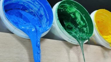 Yeşil sarı ve turuncu boyalar beyaz fıçıdan damlıyor... yüksek kaliteli 4K video. Renkli arkaplan boyası... Plastisol mürekkebi özellikle tişörtler ve kumaşlar için..
