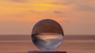 .Kristal kürenin içinde gün batımında muhteşem bir gökyüzü kristal küreyi sular altında bırakan denizin yansımasında su yüzeyinde parlak sarı gökyüzünün yansıması...
