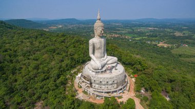 .Tayland 'ın Mukdahan kentinde 15 Mayıs 2017 tarihinde Wat Roi Phra Phutthabat Phu Manorom' u ziyaret edip namaz kılan insanlar için dağdaki büyük beyaz Buda heykeli. Kong Nehri arkaplanı..