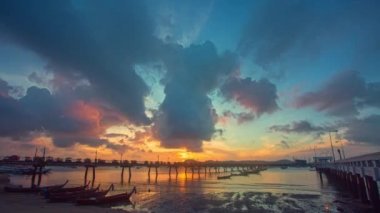 Gün doğumunda Chalong rıhtımında zaman ayarlı balıkçı tekneleri. Tatlı sarı ışık ışınları ve diğer atmosferik efektlerle gün doğumu. Deniz arka planında gün doğumunun renkli yansıması..