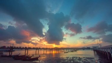 Gün doğumunda Chalong rıhtımında zaman ayarlı balıkçı tekneleri. Tatlı sarı ışık ışınları ve diğer atmosferik efektlerle gün doğumu. Deniz arka planında gün doğumunun renkli yansıması..