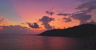 Tayland 'daki adanın üstündeki bulutların arasından geçen renkli pembe bir ışık.