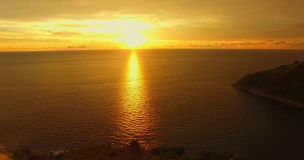 海の表面にカラフルな空の影響で太陽が沈む空を見る 崖の美しさは美しい日没の魅惑的な性質と完璧にフィットします 雲の景色背景4Kカラフルな黄金の夕日空 — ストック動画