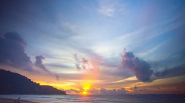 Güneşten gelen ışık ışınları renkli bulutlara nüfuz etti. Muhteşem sarı güneş adanın arkasından doğmaya başladı.. 